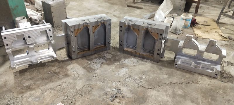 Complete two-cavity blow mould set laid out on the tool room floor.