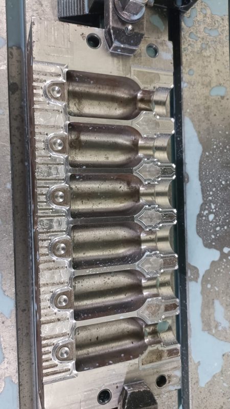 Six-cavity pharmaceutical bottle mould on the machine, cavities polished.